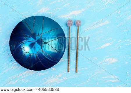 Hang Musical Instrument, Glucophone. Metal Tongue Drum, Blue Background. Top View Copy Space