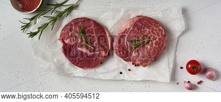 Two Fresh Parisienne Raw Steak On White Parchment Paper With Salt, Pepper And Rosmary In A Rustic St