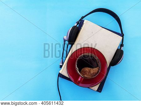 Audio Book Concept. Black Headphones With Books And Cup Of Fresh Coffee On Blue Background. Top View