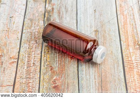 A Macro Shot With Selective Focus Of An Amber Color Vaccine Injection Vial Set On A Wood Background.