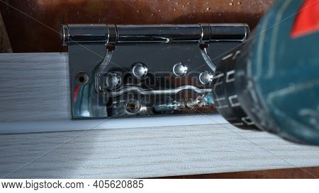 Shiny Metal Fastener With Holes On The Light Wood Strip Under The Pressure Of The Tool Screwing The 