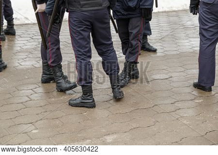 Russian Police Officers Legs In Black Ankle Boots, Red Stripe Pants And With Rubber Tonfa Night Stic