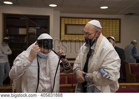 Jerusalem, Israel - January 28th, 2020: A Boy Putting His Tefillin On In A Synagogue, Watched By His