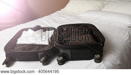 A businessman's open suitcase on top pof a hotel bed with intentional flare from a window.