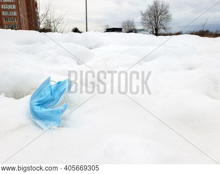 Dirty Surgical Or Medical Mask With Rubber Ear Straps On The Ground. Typical 3-ply Doctor Mask To Co