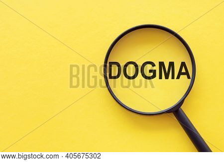 The Word Dogma Is Written On A Magnifying Glass On A Yellow Background.