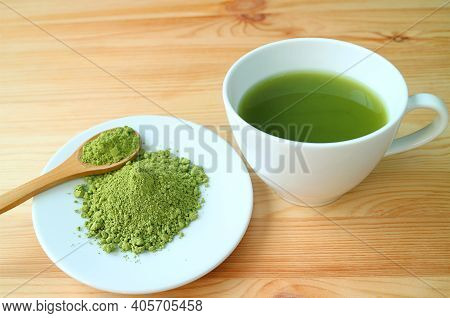 Plate Of Matcha Tea Powder With A Cup Of Hot Matcha Green Tea On Wooden Table