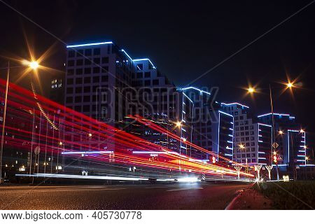 Horizontal Long Exposure Photo With Red Speed Light Of Fast Moving Cars Against Modern Illuminated B