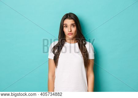 Image Of Clueless Young Brunette Girl, Wearing White T-shrit, Shrugging And Looking Pitiful, Standin