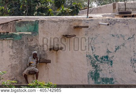 Aihole, Karnataka, India - November 7, 2013: Older Man Has Lunch While Sitting On Peculiar Steps On 