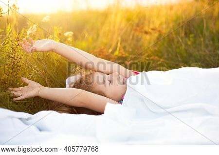 Girl Sleeps On Bed In Grass, Sweet Stretches And Yawns Sleepily, Good Morning In Fresh Air. Eco-frie