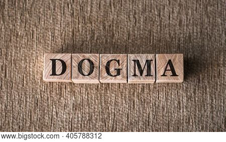 Dogma Word Written On Wooden Blocks On A Brown Background.