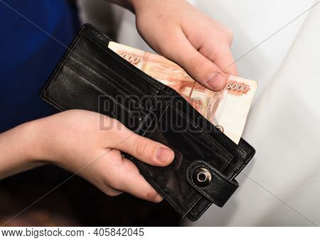 Young Man Takes Out  5000-ruble Banknote From  Black Wallet. Russian Cash. Finance.