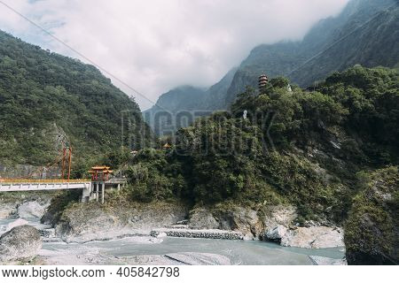 Wide View Of Xiangde Temple From Valley Below With River And Sharp Cliffs Behind.
