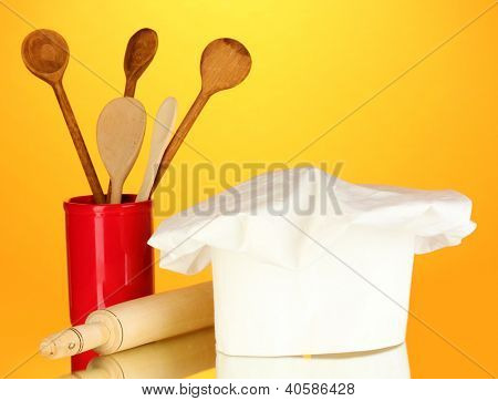 Kochmütze mit Löffel und Federballschläger auf orange Hintergrund