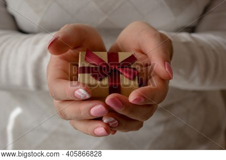 Woman Hands Holding A Small Present Box With Red Ribbon Over. Valentine Gift Box. Close Up Shot Of F