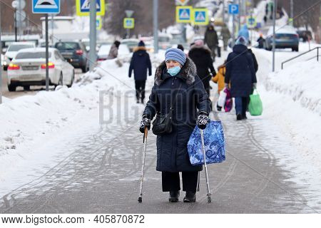 Moscow, Russia - January 2021: Elderly Woman In Medical Mask Walking With A Canes And Bag On A City 