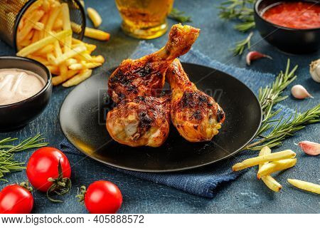 Still Life Of Three Grilled Chicken Legs With Crunchy Golden Brown Crust Served On A Black Plate Wit