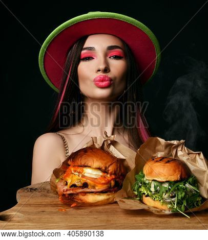 Beautiful Woman Hold Two Craft Big Burger Sandwiches With Hungry Mouth And Steam Smoke In Green Hat 