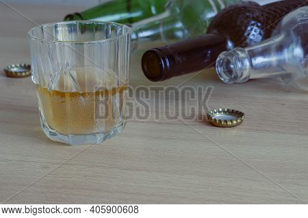 A Glass Of Beer, Empty Bottles And Corks On The Table. Alcohol Addiction Is A Concept. A Social Prob