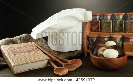 Sammansättning med kockens hatt och kitchenwear på bordet på grå bakgrund