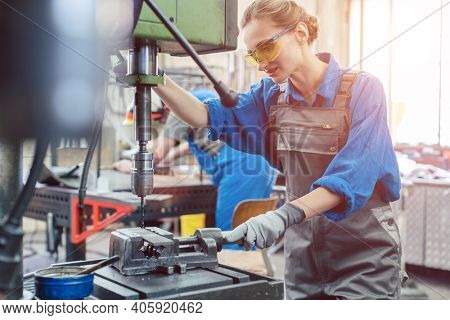 Metal worker woman operating drilling machine concentrating on her job