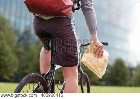 Bicycle Messenger Courier Delivers Urgent Shipment Parcel In Urban Park
