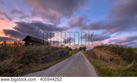 Road Passage Through Dike At Sunset Under Beautiful Clouded Sky. Usquert, Groningen, Netherlands