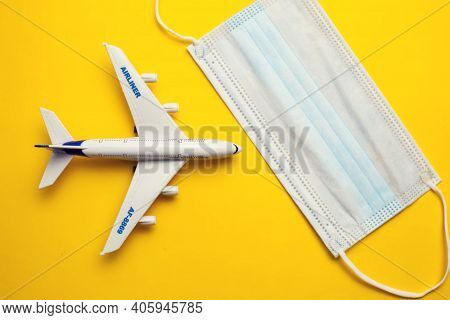 Savety Travel During Covid-19 Pandemic. Plane With Medical Face Mask On Yellow Background. Coronavir