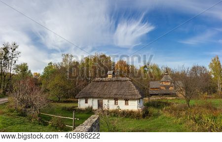 Landscape With Old Ukrainian Wooden Rural House With Thatched Roof Built In The 19th Century, Agains