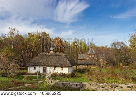 Landscape With Old Ukrainian Wooden Rural House With Thatched Roof Built In The 19th Century, Agains