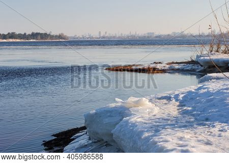 Wide Plain River Partially Covered With Thin Ice, Thick Ice Floes On The Shore On A Foreground Again