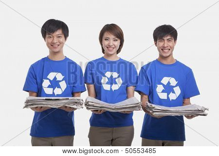 Three young people carrying newspapers, studio shot