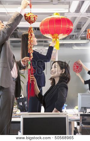 Coworkers hanging decorations in office for Chinese new year