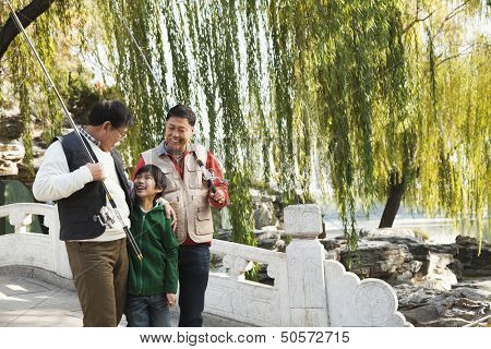 Multi-generational men walking with fishing gear at lake