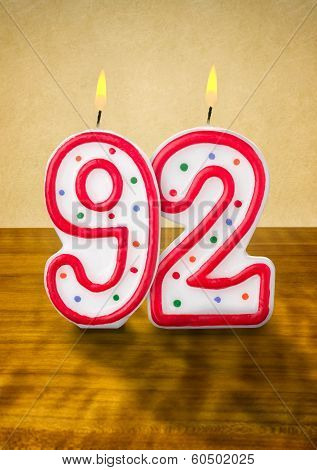 Burning birthday candles number 92 on a wooden background