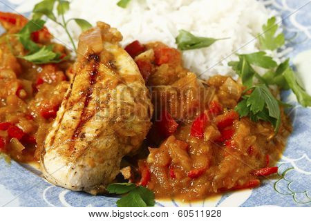 Grilled marinaded chicken served with a spice tomato and red capsicum salsa, in the Caribbean style, and white rice, all garnished with parsley.