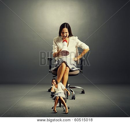 emotional businesswoman screaming at fatigued woman over dark background