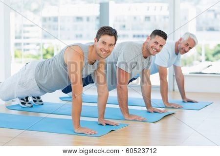 Portrait of happy fit men doing push ups at gym