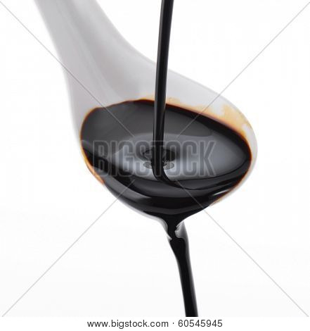 Soy sauce flowing over spoon isolated on white background