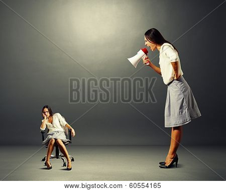 big angry businesswoman screaming at lazy woman over dark background