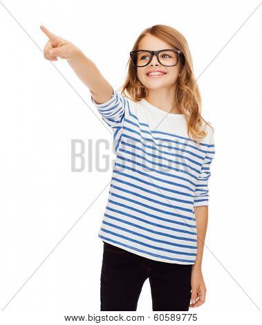 education, school and imaginary screen concept - cute little girl in eyeglasses pointing in the air or imaginary screen