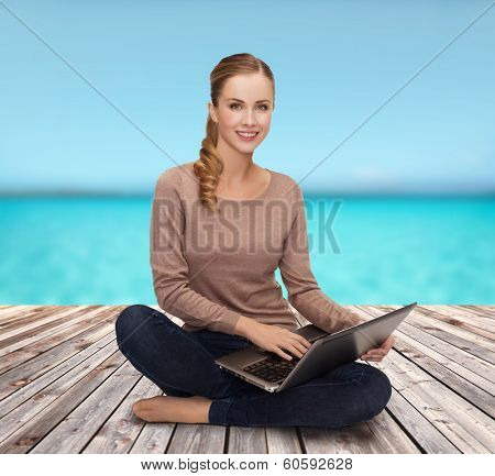 happiness, internet, technology and people concept - smiling young woman sitting on floor with laptop computer