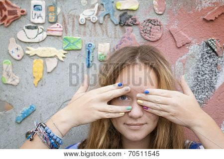 Cute cheerful young girl covers his eyes with his hands.