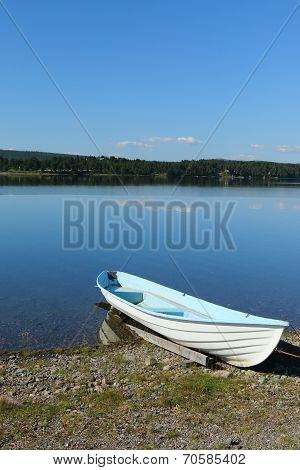 Rowing boat moored on calm lake shore