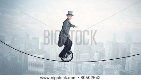 Brave guy riding a monocycle on a rope above cityscape concept