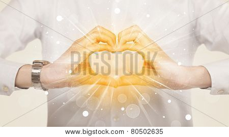 Hands creating a form with yellow shines in the center