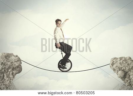 Brave business man riding an mono cycle between cliffs concept