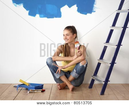 Portrait of female painter sitting on floor after painting.