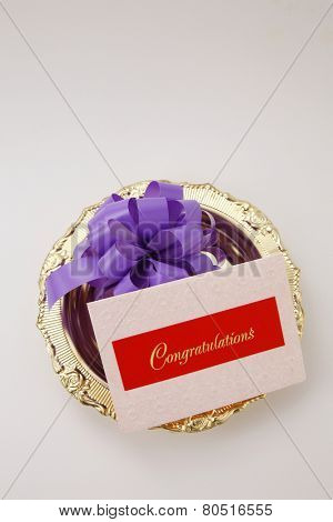 top view purple ribbon bow and a congraturation card